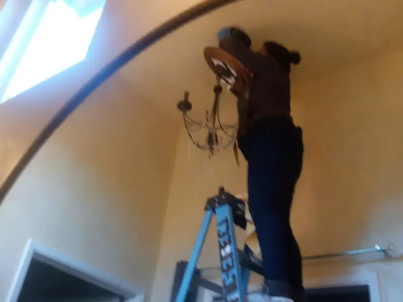 Electrician installing a chandelier in a Plainview residence